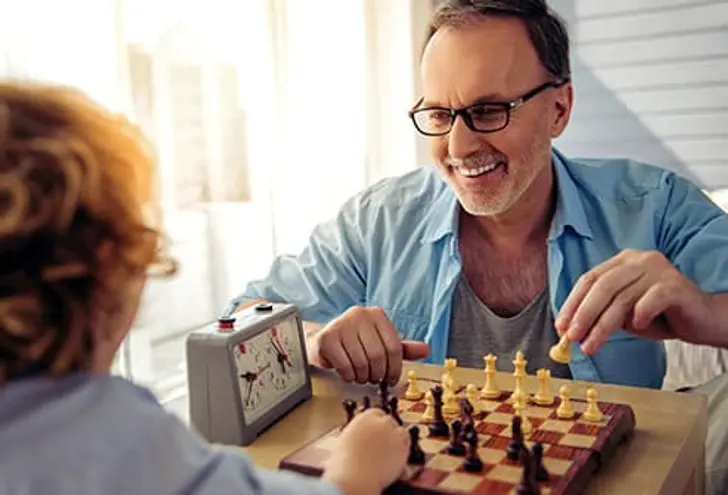 A man and a child engaged in a game of chess, focused on the board with pieces in play between them.
